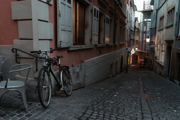 Fototapeta na wymiar Zurich, Switzerland - June 19, 2019: Street in old Zurich, Switzerland. Empty street at a sunset time with a bike in foreground