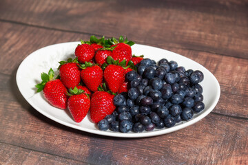 Fresh Bowl of strawberries and blueberries on a wooden table.