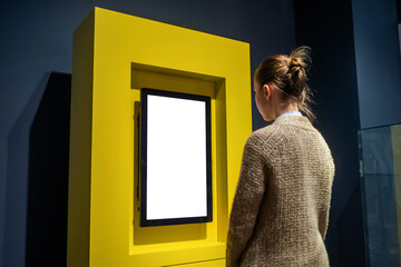 Woman looking at vertical blank digital interactive white display wall at exhibition or museum with...
