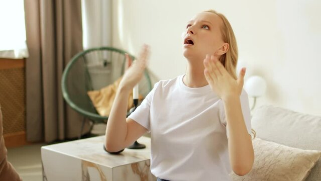 Overheated sweating woman feeling hot. Suffering from high temperature at home and heat without air-condition or climate control system. Breathing deeply and waving hands to cool down.	