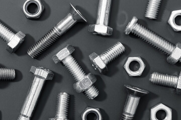 Creative background of a variety of metallic nuts and bolts on black background. Full frame