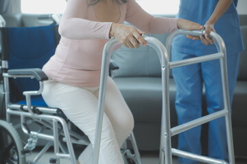 Asian young woman nurse at nursing home take care disabled senior man. Caregiver doctor serve physical therapy for older elderly patient to exercise and practice walking on walker or cane at backyard.