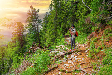 Hiker young woman on a forest path with a camera.