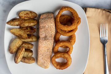 baked salmon  served with onion rings and potato wedges