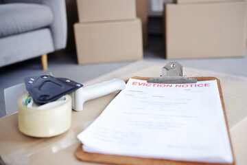 Its time to leave. Shot of an eviction notice and a tape dispenser on a cardboard box in an empty living room.