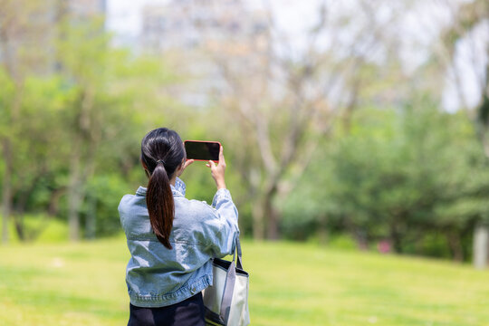 Woman use cellphone to take photo in the garden