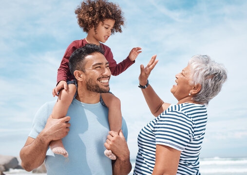 Give grandma a high-five. Shot of a little boy at the beach with his father and grandmother.