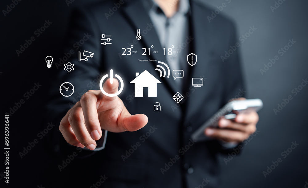 Poster Smart home digital remote control on smartphone concept. internet of things in technology control. Businessman holding wooden house with virtual smart home icon function.