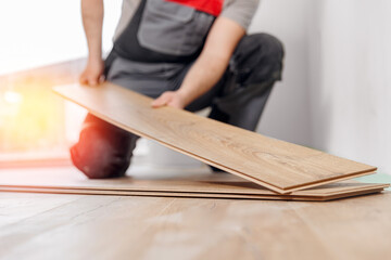 Professional builder man laying laminate flooring at home