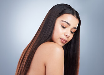 Fototapeta premium Beautiful young woman with shiny brown and straight long hair. Young girl looking down at her shoulder and showing off healthy-looking hair