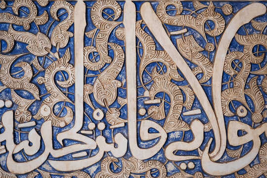 Details of stucco decoration with an Arabic writings painted in blue on the Palaces walls in Alhambra complex, Granada, Andalusia, Spain.