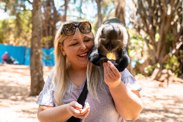 Woman with a Sykes monkey (also known as a blue money) in Nairobi City Park, on her back © MelissaMN