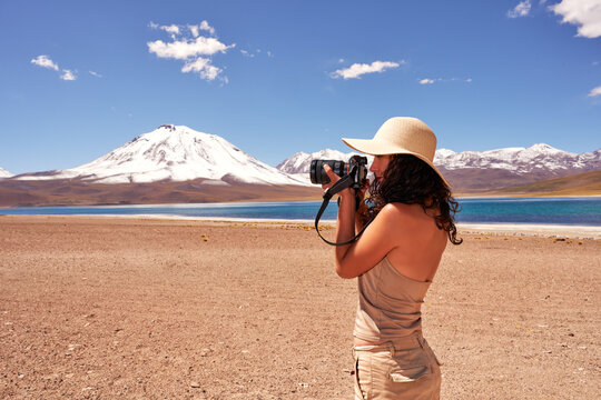 young woman taking pictures with a professional camera at the Miscanti Lake in Los Flamencos National Reserve