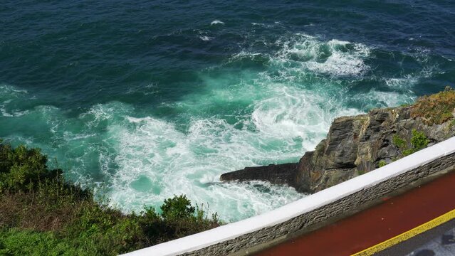 Slowmotion of waves crashing against the rocks at the foot of a lighthouse in northern Spain, Asturias.