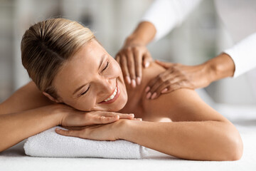 Fototapeta na wymiar Spa Relax. Beautiful Middle Aged Female Enjoying Massage Session In Wellness Center