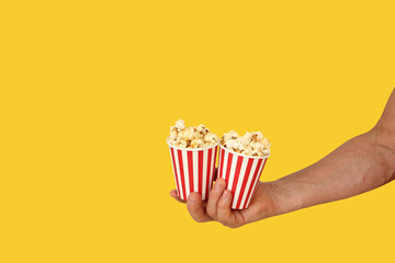 two red striped paper cups with fried on yellow background, concept of mass culture aimed at entertainment, fun party, various means of popularization and commercial promotion