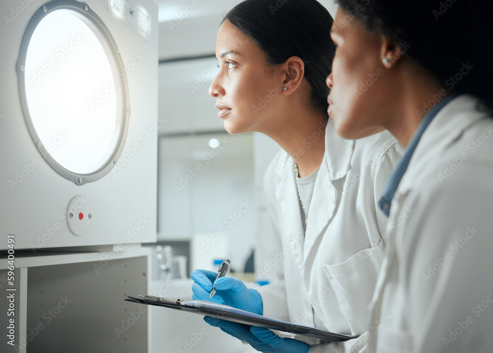 Poster patience is key when it comes to this. shot of two female scientists looking through a door waiting 