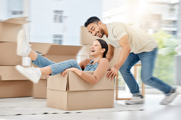 Caught up in a whirlwind of excitement. Shot of a young couple playing with boxes while moving...