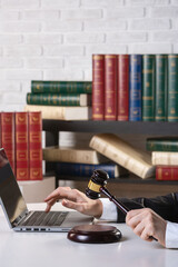 Female hands in formal wear with maroon auction gavel and open laptop on a desk in an office, vertical photo, selected focus.