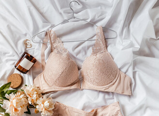 Gentle beige lace bra on the bed. Women tender lingerie, underwear. Top view, close up. Flat lay, beauty blog or social media minimal concept. Present for Valentines, Women’s day	 - obrazy, fototapety, plakaty