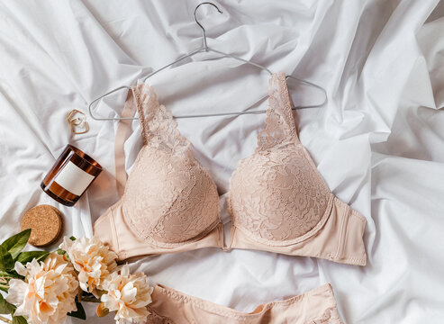 Gentle beige lace bra on the bed. Women tender lingerie, underwear. Top view, close up. Flat lay, beauty blog or social media minimal concept. Present for Valentines, Women’s day	
