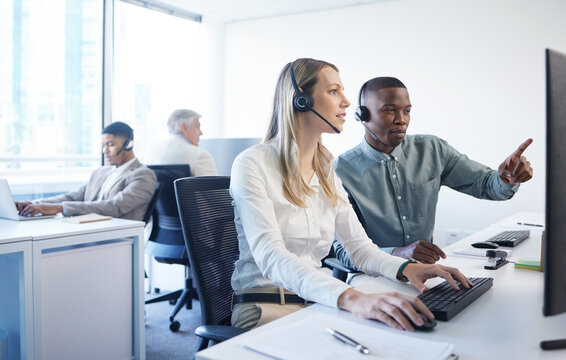 Your concern is their concern. Shot of a businessman and businesswoman using a headset and computer while working in a modern office.