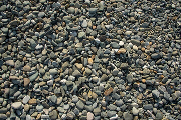 Different color beach stone pebbles at seashore outdoors top view. Abstract smooth round pebbles sea