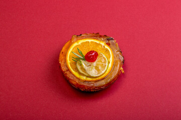 Cheese cake with marmalade and lime and orange slices on a red background