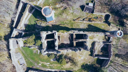 Aerial shot of the castle in the middle of the woods. A ruined castle located on a hill in the middle of the woods. Medieval castle tower.