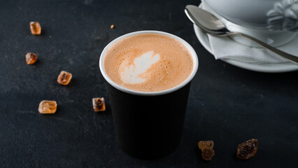 Paper cup of hot cappuccino coffee with sugar.