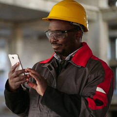 African american workman with smartphone at construction site