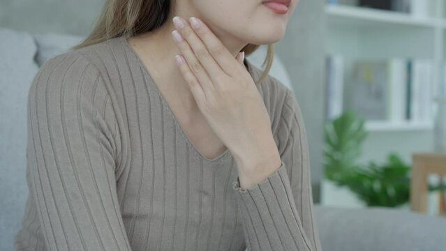 Aisa woman put her hand on her neck due to a sore throat. female tonsillitis causes a inflammation. treated by taking water, taking antibiotics, consult a doctor, virus, corona virus, Influenza, flu