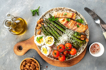 Baked chicken breast wrapped in bacon with asparagus, eggs and cherry tomato, Healthy fats, clean eating for weight loss. Keto paleo diet menu, top view