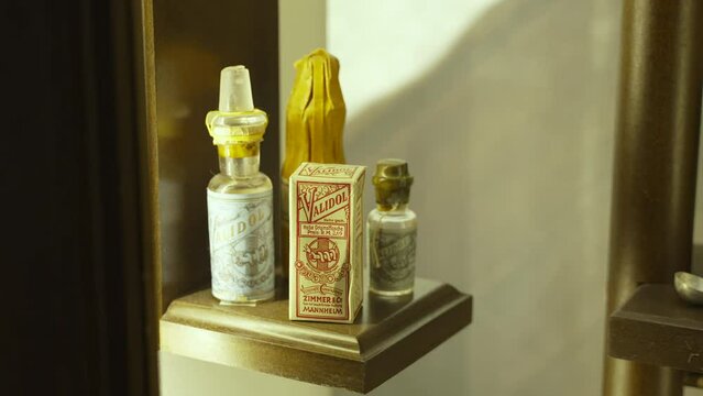 Old German drug Validol from early 20th century. Glass jars, cardboard packaging of medicines on shelf in cupboard with warm light. Ineffective, unsafe and outdated remedy in modern medicine.