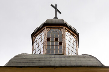 Old church tower with broken windows and with a cross on top