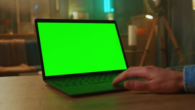 Close up man hands of freelancer use laptop with green screen. At home. Working. Scrolling through website. Touch keyboard