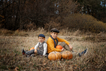 Two boys in retro clothes sitting in an autumn field. Children and pumpkins. Autumn harvest.