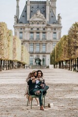 Obraz premium A couple in love walks along the streets of Paris, a guy in a coat and a suit, a girl in a dress with a beret and a trench coat in autumn with camera