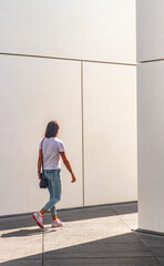 Shot of the young woman with white wall on the background. Urban