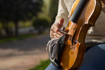 Close-up of a young woman's hand cleaning a violin in the street