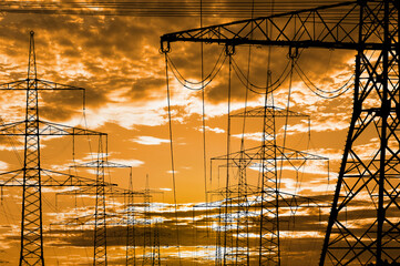 high voltage electric pylons against sky with dramatic clouds
