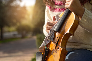 Close-up of a young woman's hand cleaning a violin in the street