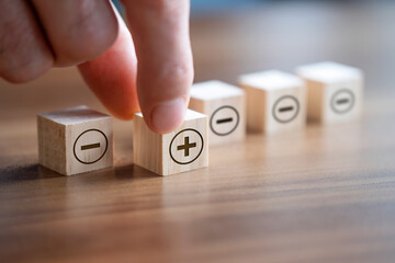 Businessman holding moving wooden block forward with positive sign on it. 