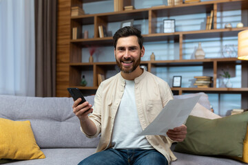 Portrait of a happy young man sitting at home on the couch. a smiling man looks at the camera,...