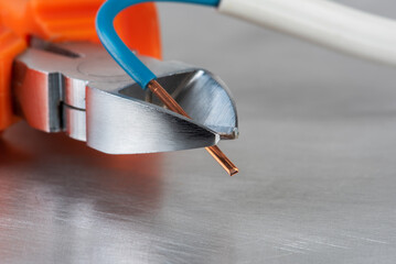 Electric wire cutters cut of copper installation electrical cable, close-up view