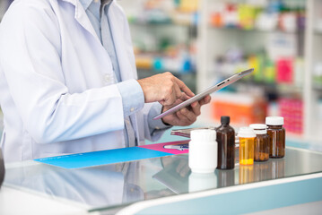 Close up pharmacist man using digital tablet for check medicine inventory in drug store, Medical service online, Telemedicine to giving medical information to online customer and patient.