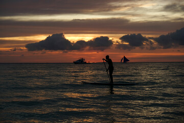 silhouette of a man on the sup board against the backdrop of sunset