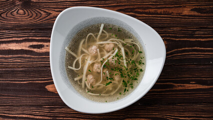 Soup with noodles and chicken meatballs in a bowl.