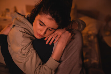 Displeased woman embracing boyfriend in bedroom at night.