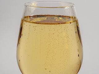 A glass of white wine on a light background.